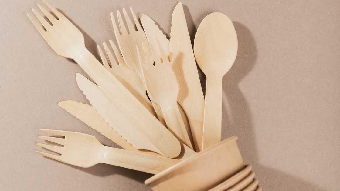 Pile of hemp bioplastic utensils falling out of a brown cup on a table